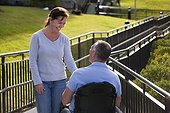 Woman meeting with husband in wheelchair with spinal cord injury on accessible ramp