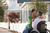 Couple enjoying each other's company in front of their home while he is in a wheelchair
