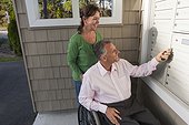 Man in wheelchair with wife getting mail from their new apartment mailbox