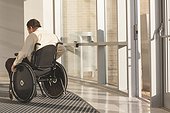 Businessman with spinal cord injury in wheelchair in a office building entrance