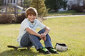 Boy sitting on his skateboard in a park