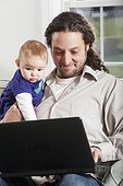 Father and baby looking at computer at home