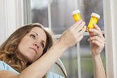 Woman at home looking at pills bottles