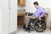 Man in wheelchair with spinal cord injury opening accessible dishwasher