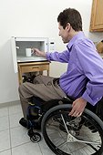 Man in wheelchair with spinal cord injury removing cup from an accessible microwave