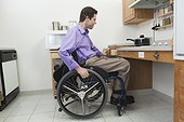 Man in wheelchair with spinal cord injury opening a drawer in an accessible kitchen