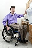 Man in wheelchair with spinal cord injury opening oven in an accessible kitchen