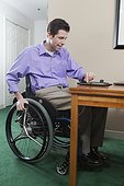 Quadriplegic man in wheelchair with spinal cord injury using his electronic tablet for e-mail