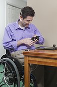 Man in wheelchair with spinal cord injury challenged with hand dexterity using his cell phone