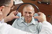Audiologist placing a headset on patient for audiometric evaluation