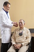 Audiologist inserting behind-the-ear hearing aid into a patient's ear during programming