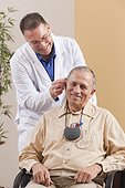 Audiologist adjusting behind-the-ear hearing aid in a patient's ear during programming