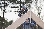 Carpenter nailing a rafter at peak