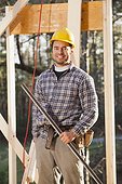 Portrait of a carpenter holding a level on house framing