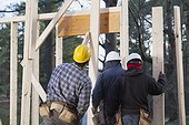 Carpenters preparing to frame exterior wall of a house under construction