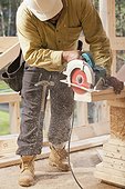 Carpenter using a circular saw on studs