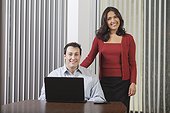 Hispanic businesswoman and businessman in office with computer