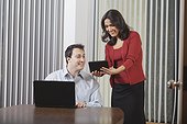 Hispanic businesswoman and businessman in office with tablet and computer