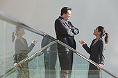Hispanic businesswoman talking with a businessman on stairwell in office building