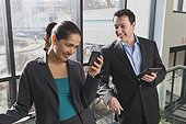 Business couple in office looking at tablet and smartphone