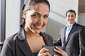 Businesswoman holding tablet with businessman behind her
