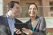 Business couple talking and smiling with a tablet