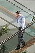 Businessman talking on mobile phone walking down stairs