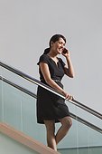 Businesswoman talking on mobile phone walking down stairs