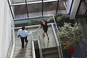 Business couple joyfully walking down stairs of office building