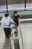 Business couple looking at computer on stairs in office building