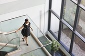 Hispanic businesswoman with briefcase on stairs on office building