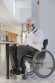 Doctor with muscular dystrophy in wheelchair talking on smartphone