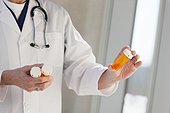 Doctor reading labels of pill bottles