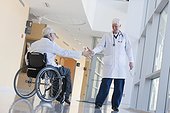 Doctor with muscular dystrophy in wheelchair shaking hands with another doctor