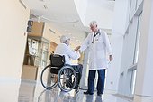 Doctor with muscular dystrophy in wheelchair shaking hands with another doctor