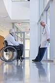 Doctor with muscular dystrophy in wheelchair talking with another doctor