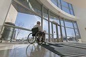 Doctor with muscular dystrophy in wheelchair at hospital entrance