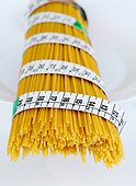 Uncooked spaghetti tied with a tape measure