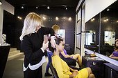 Hairdresser brushing customer's hair in hair salon