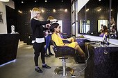 Hairdresser brushing customer's hair in hair salon