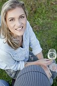 Woman with blond hair drinking wine on garden party
