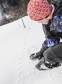 Girl touching the animal tracks on snow in Black Forest, Germany, Europe