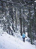 Woman hiking through snowy forest in Valley of Yach, Elzach, Black Forest, Baden-Württemberg, Germany