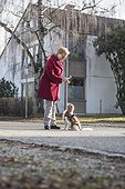 Old woman and dog standing on the street with toy