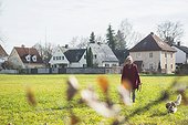 Old woman walking on meadow with pet dog