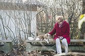 Old woman and her dog sitting outside on bench