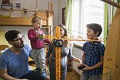 Two brothers and parents are playing with a toy crane, Munich, Germany
