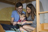 Parents reading a book to their son on the bunkbed, Munich, Germany