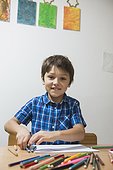 Boy enjoying with coloured pencils while looking at camera, Munich, Germany