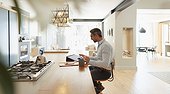 Businessman at digital tablet working from home in modern kitchen
